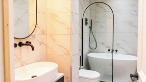A modern bathroom with a freestanding bathtub, a toilet, and a sink. - Stunning Victorian apartment with garden (London)