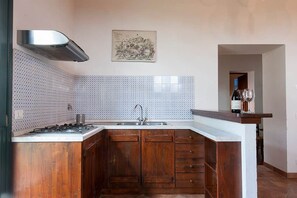 Une cuisine équipée d’une cuisinière à gaz, d’un évier, de meubles en bois et d’un pare-feu.