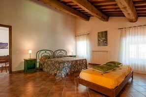 A bedroom with a wooden bed, two bedside tables, a chair, a radiator, and a window with curtains.