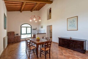Un vaste espace dédié à la salle à manger, avec une table et des chaises en bois, un buffet en bois foncé et un luminaire suspendu.