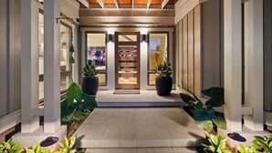 A modern entrance with a wooden ceiling, potted plants, and a glass door. - Hale Honu Kukui'ula By Suite Paradise (Koloa)