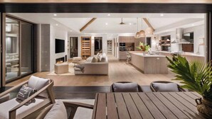 A modern open-plan living area with a fireplace, sofa, and dining space. - Hale Honu Kukui'ula By Suite Paradise (Koloa)