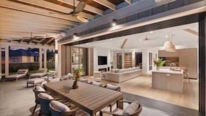 A modern open-plan living area with a dining table, sofas, and a kitchen area. - Hale Honu Kukui'ula By Suite Paradise (Koloa)