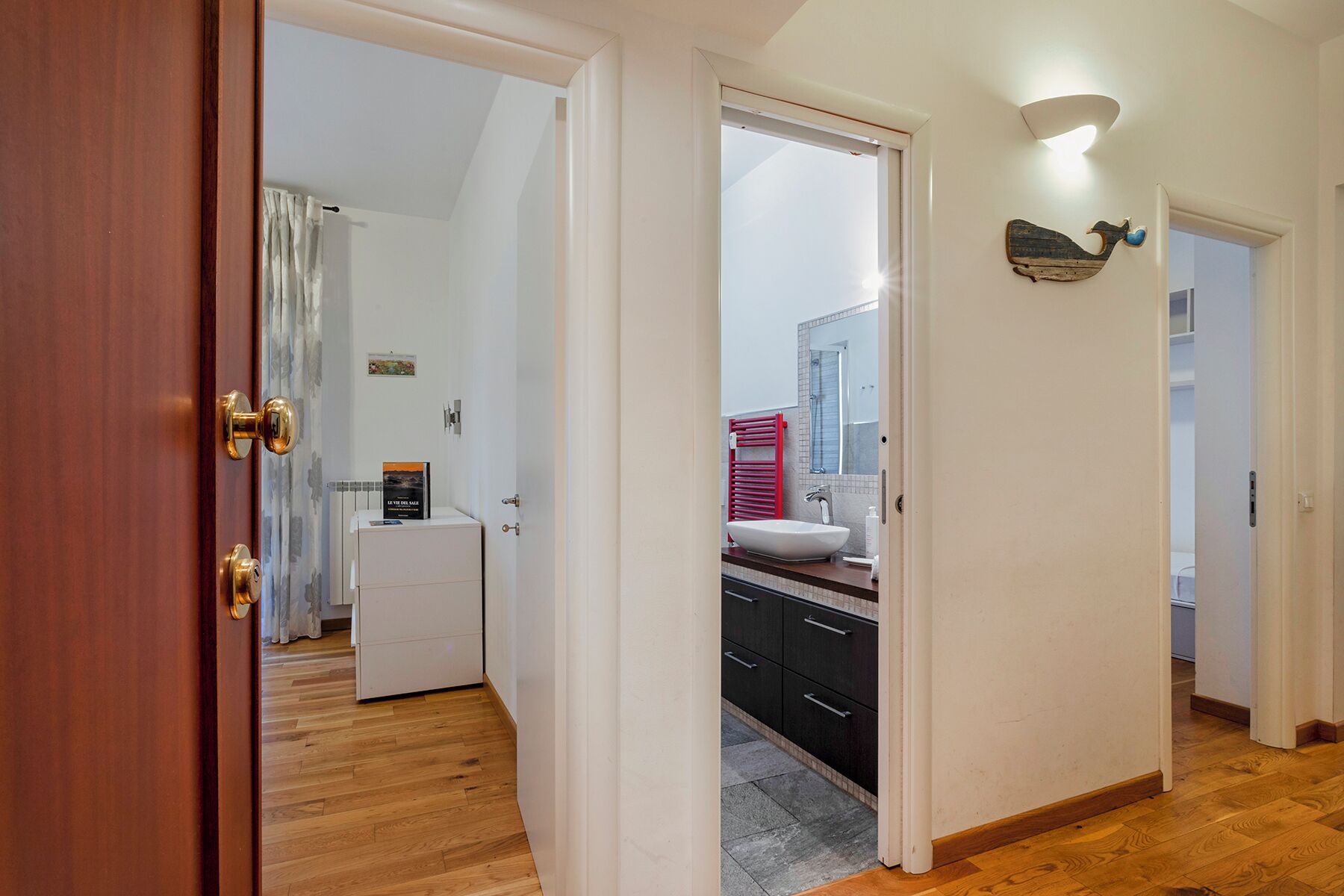 Une salle de bain moderne avec un lavabo blanc, un porte-serviettes rouge et un miroir.
