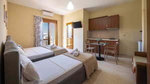Una habitación de hotel con dos camas, una kitchenette pequeña, un comedor y un baño.