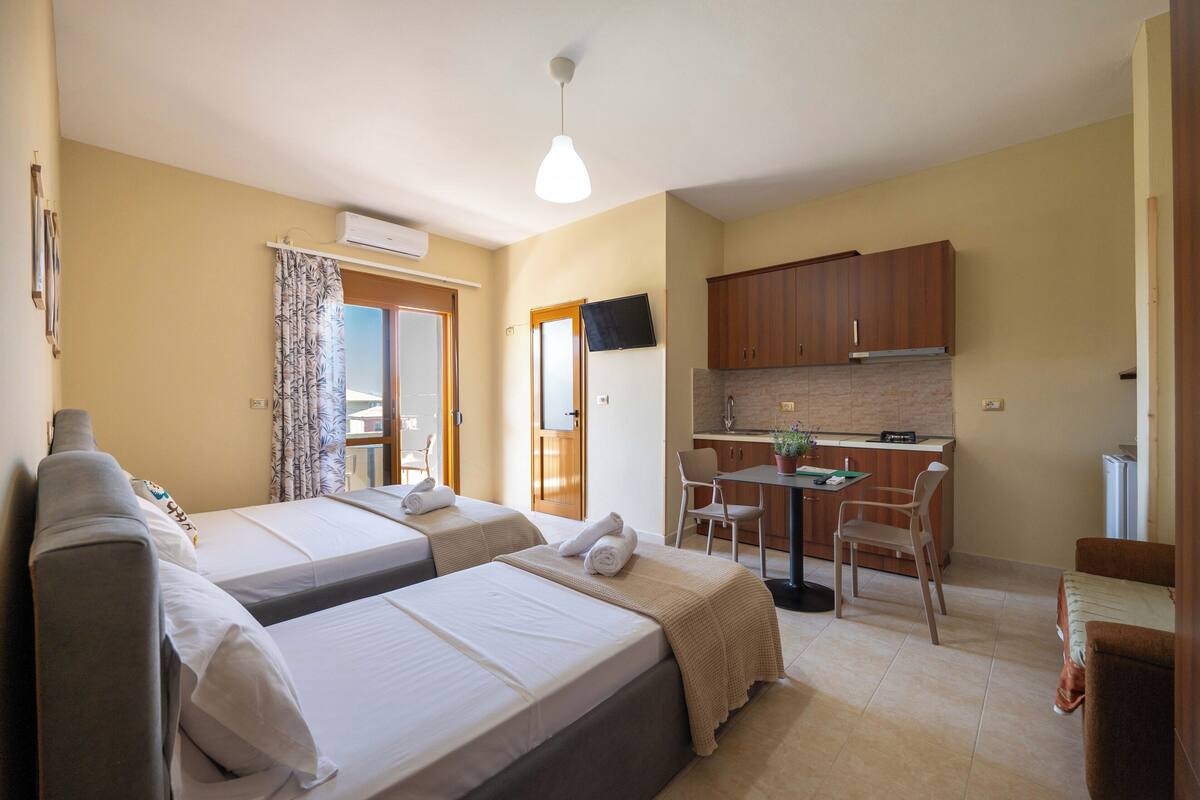 Une chambre d’hôtel avec deux lits, une petite kitchenette, un coin repas et une salle de bain.