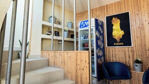 Interior de hotel con paneles de madera, un refrigerador, una silla azul y un mapa de Albania en la pared.