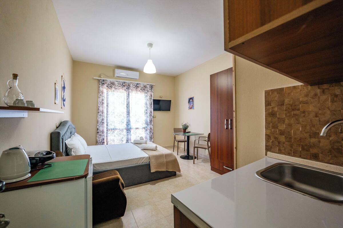 Une chambre d’hôtel de taille réduite comprenant un lit, une petite kitchenette, un coin repas et une salle de bain.