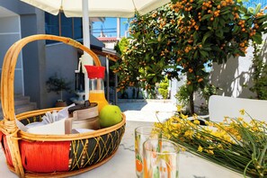 A wicker basket with a red interior, containing a green apple, a glass bottle, and a white container. - Kalpazo Kaja Vila Garden (Golem)