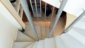 Una escalera con barandillas de metal que lleva a una habitación con piso de madera y pared blanca.