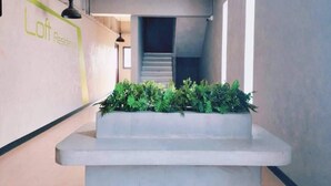 A modern reception area with a central planter and a staircase in the background. - Capital O 75512 Loft Residence (Suphan Buri)