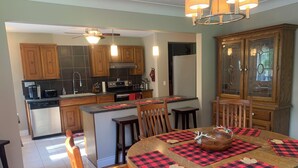 Una cocina moderna con armarios de madera, una isla central y una zona de comedor con una mesa redonda y sillas.