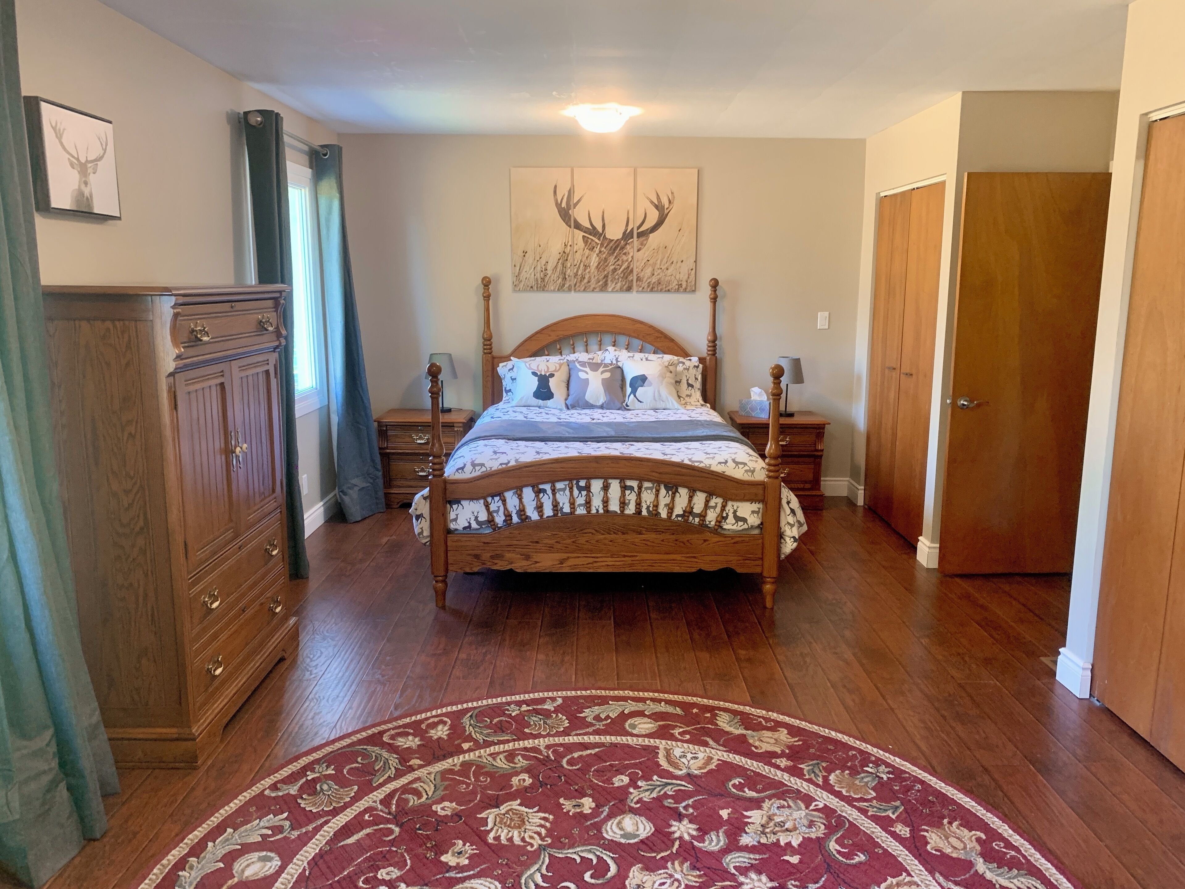 Une chambre à coucher avec un lit en bois, une table de chevet, une commode, une porte et un tapis à motifs.