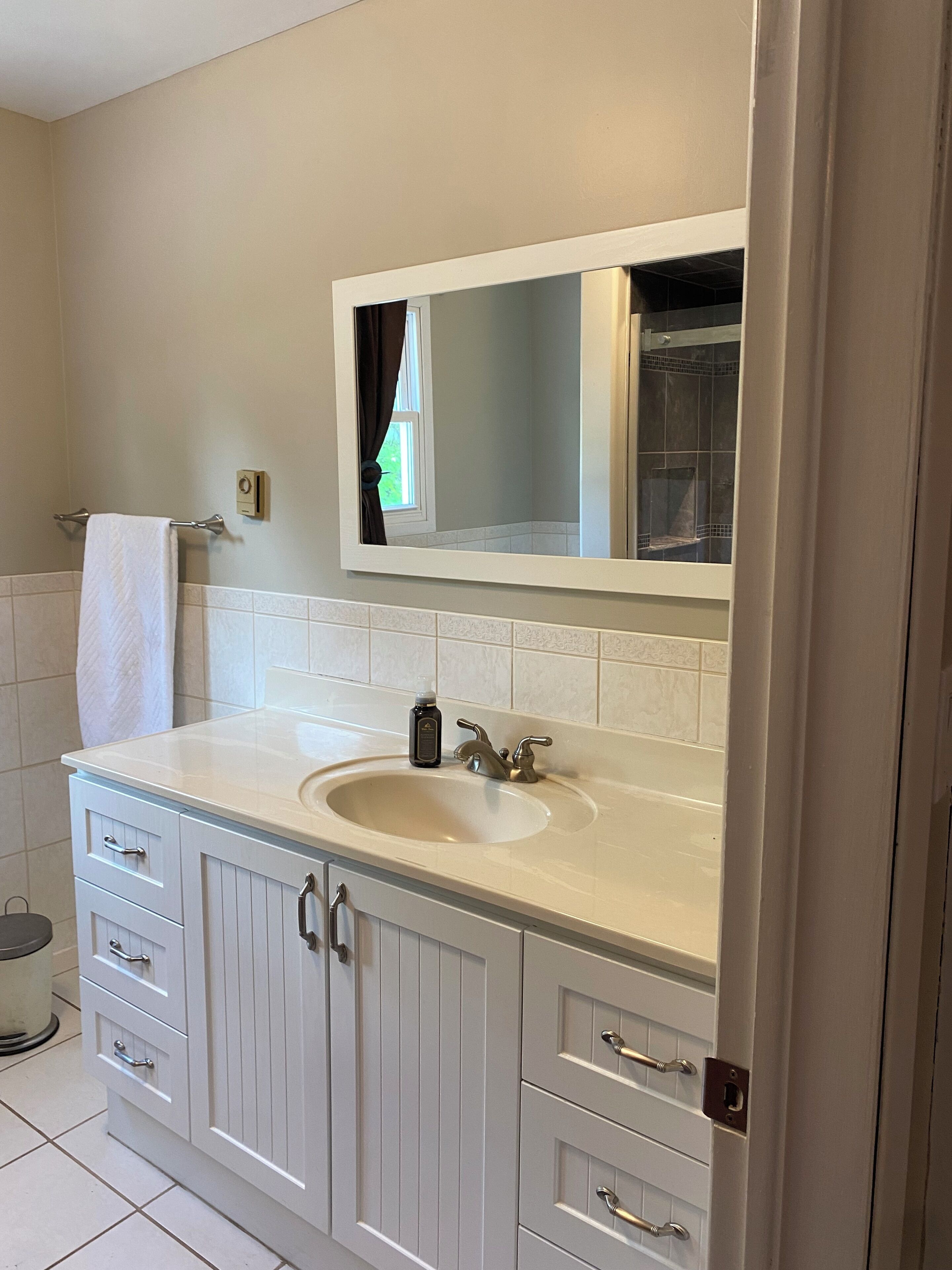 Une salle de bain avec un meuble-lavabo blanc, un évier et un miroir au-dessus.