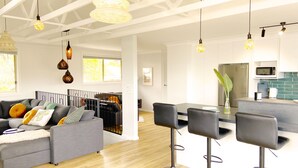 A modern living room with a grey sofa, black bar stools, and a dining table. - Treeview - A Beautiful 3-bed House in Kiama (Kiama)