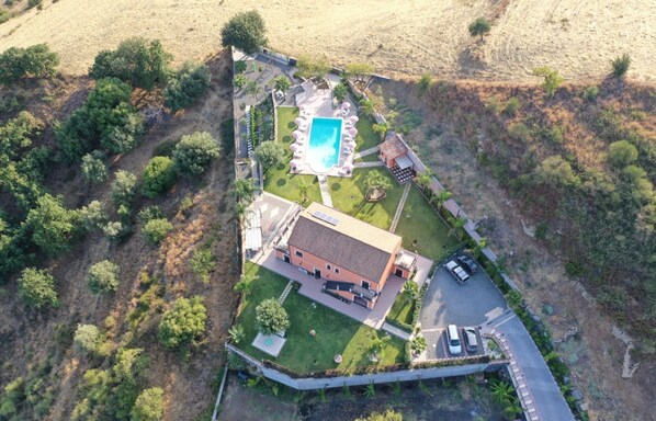 Vista aérea de una propiedad con piscina, una casa grande y un estacionamiento.