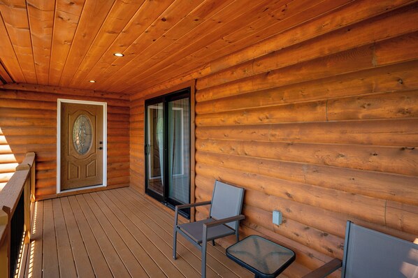 Une terrasse en bois avec une porte, une fenêtre et une chaise.