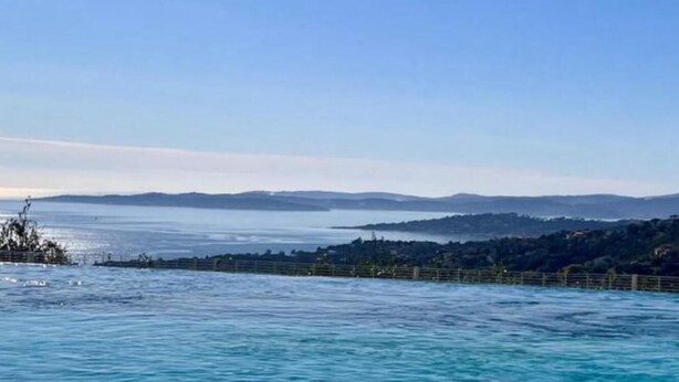 Une vue sur la côte, avec une clôture et des collines à l’horizon.