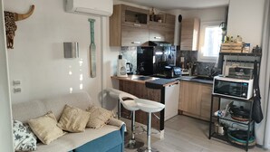 Une cuisine compacte dotée d’appareils électroménagers modernes, un coin repas avec un canapé et un tabouret de bar.