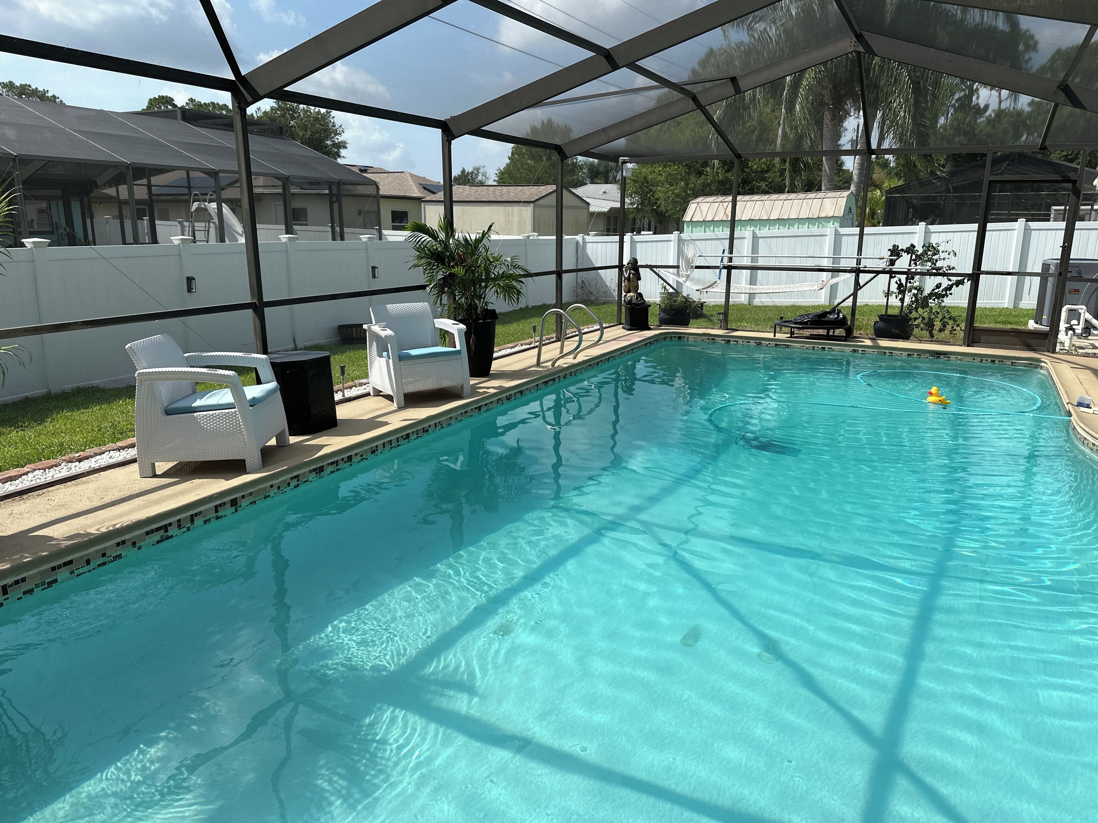 Una piscina con zona cubierta, sillas de descanso blancas y agua azul cristalina.