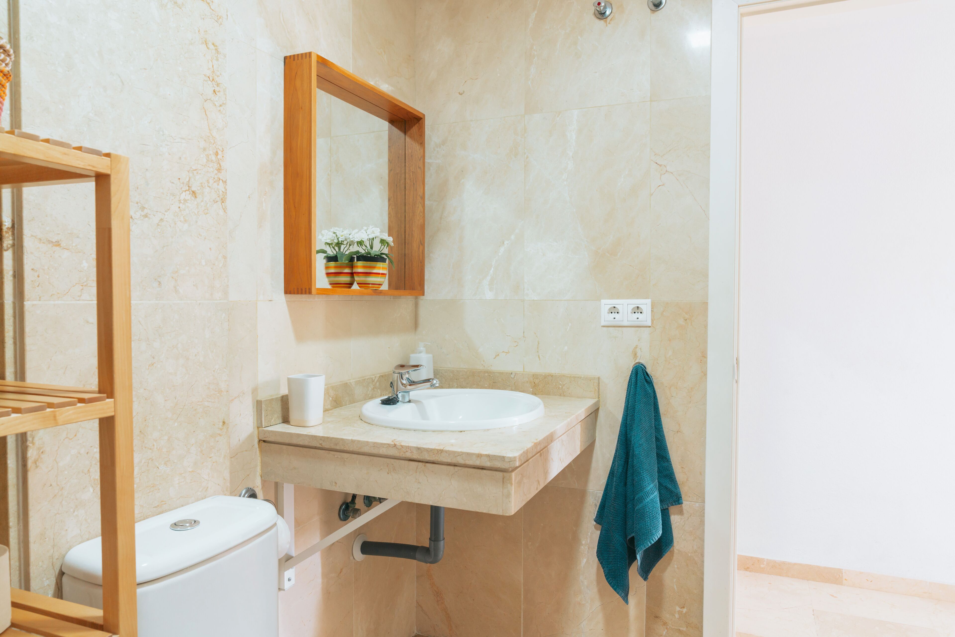 Un baño con inodoro, lavamanos, espejo y toallero.