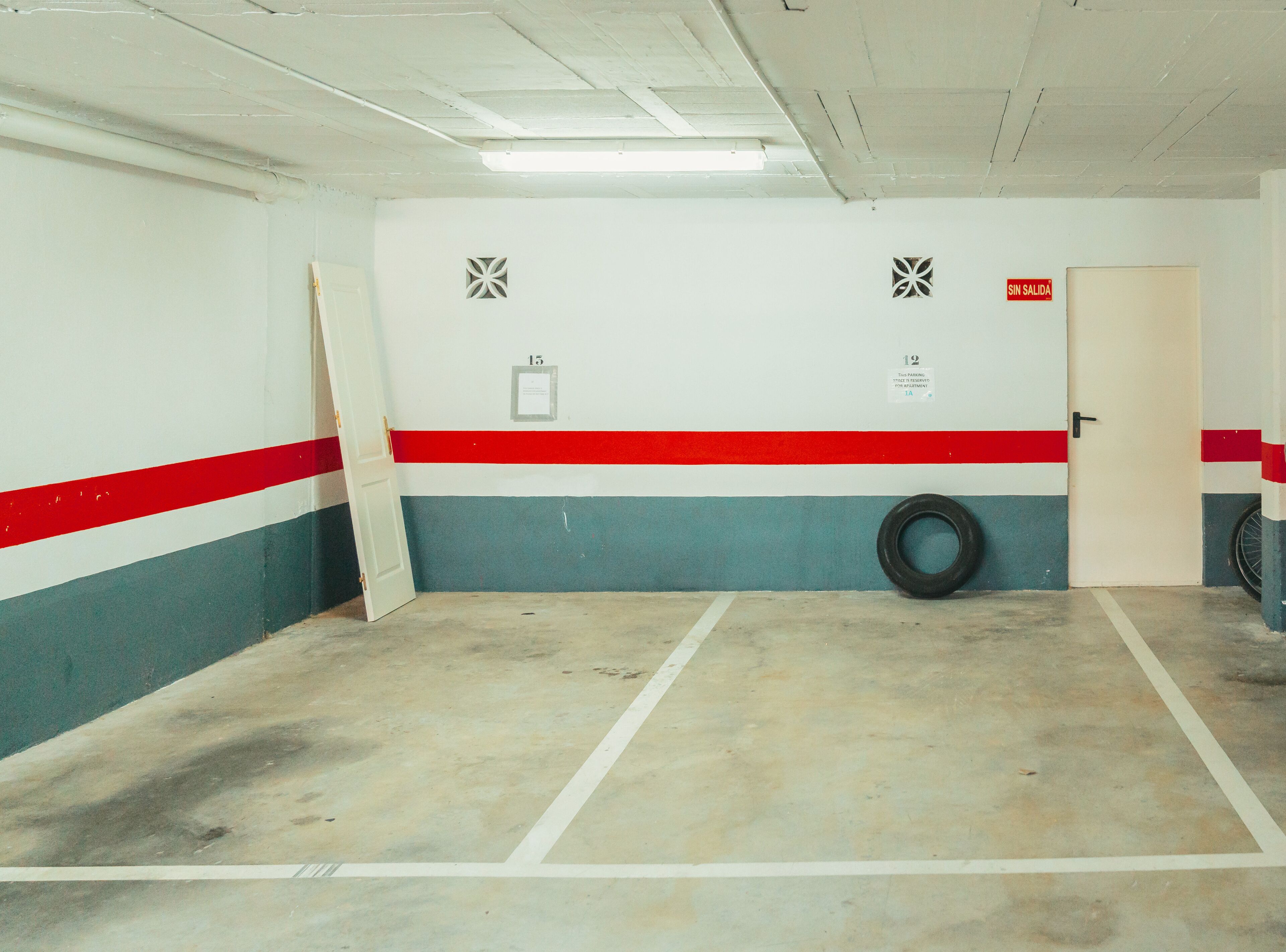 A parking garage with white walls, red and blue stripes, and numbered parking spaces.