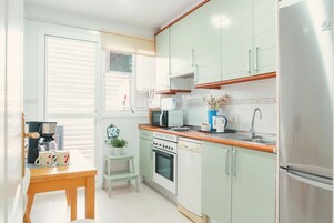 A compact kitchen with a microwave, oven, dishwasher, and a stainless steel refrigerator.
