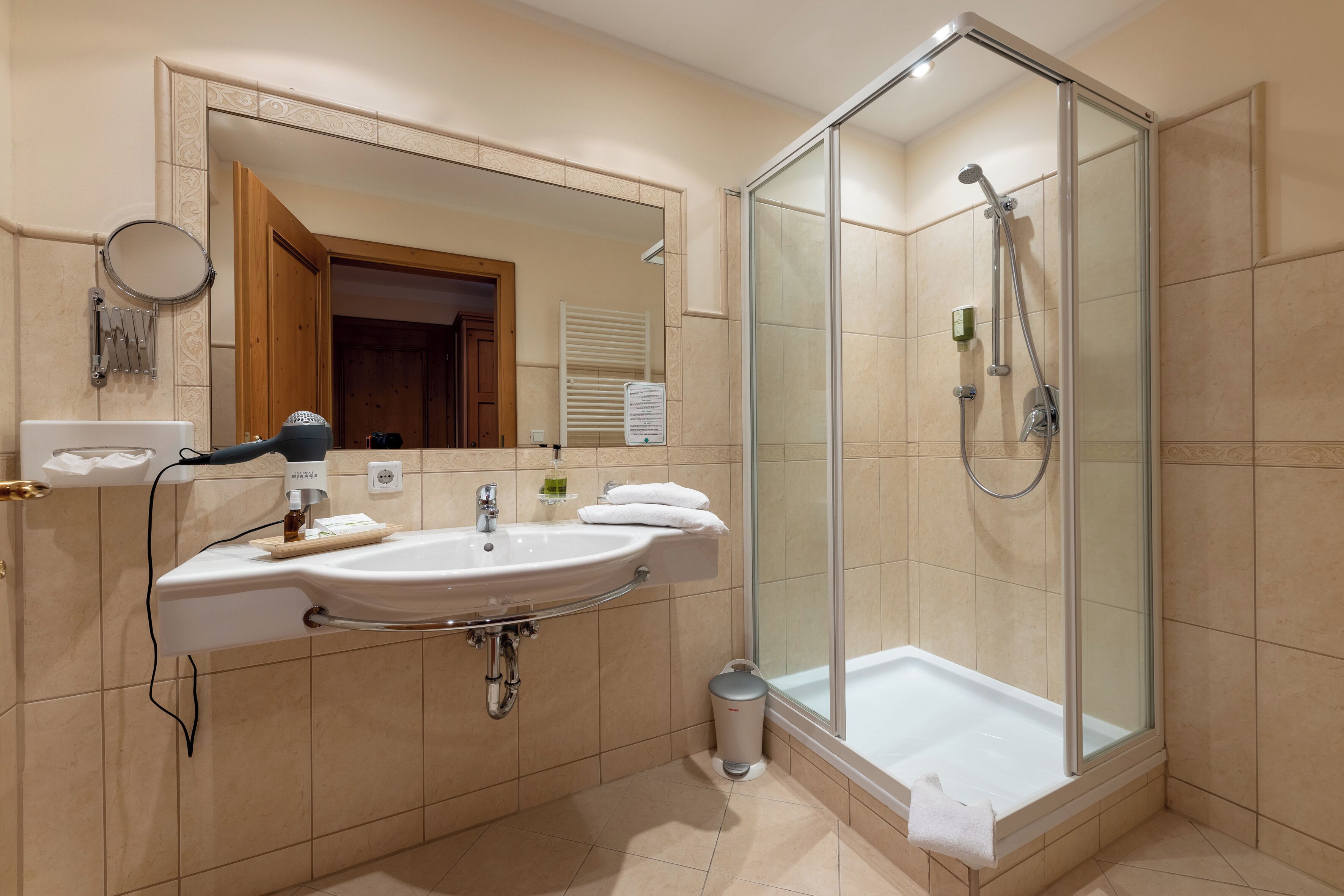 A modern bathroom with a glass-enclosed shower, a sink with a mirror, and a towel rack.