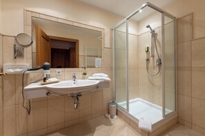 A modern bathroom with a glass-enclosed shower, a sink with a mirror, and a towel rack. - Hotel Gletscherblick (Sankt Leonhard im Pitztal)