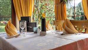 A table set for two with a vase of flowers, a wine glass, and a menu card. - Hotel Gletscherblick (Sankt Leonhard im Pitztal)