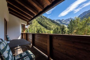 A wooden deck with a table and chairs, overlooking a mountainous landscape. - Hotel Gletscherblick (Sankt Leonhard im Pitztal)