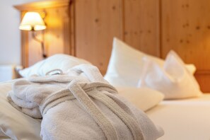 A neatly made bed with white pillows and a beige bathrobe draped over it. - Hotel Gletscherblick (Sankt Leonhard im Pitztal)