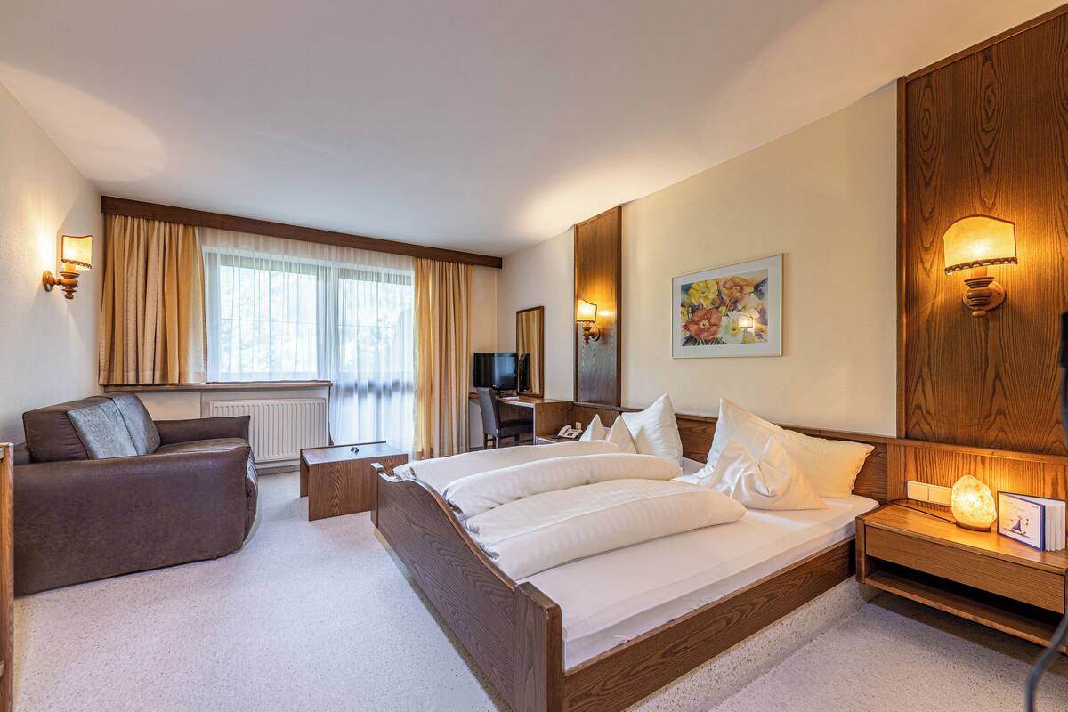 Una camera d'albergo con un letto, un divano, una scrivania e una televisione.