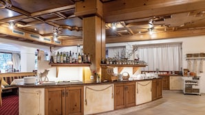 A spacious kitchen with a large island, wooden cabinets, and a variety of kitchen appliances. - Hotel Gletscherblick (Sankt Leonhard im Pitztal)