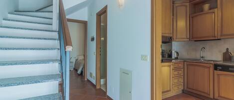 A staircase leading to a bedroom with a view of the kitchen.