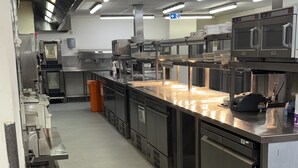 A commercial kitchen with stainless steel appliances, including ovens and a large countertop. - Luxe Apartment - Stylish 2 Bedroom Apartment (Harrow)