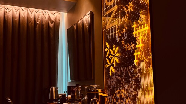 A dimly lit room with a table set for dining, featuring a coffee pot, wine glass, and glasses. - Luxe Apartment - Stylish 2 Bedroom Apartment (Harrow)