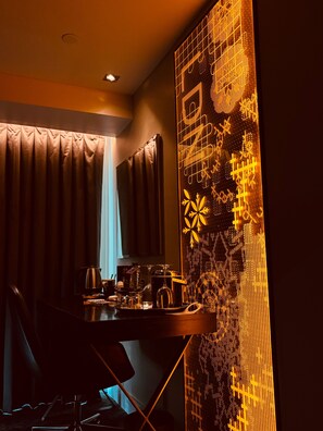Ein schwach beleuchteter Raum mit Esstisch, der mit einer Kaffeekanne, einem Weinglas und Gläsern gedeckt ist.