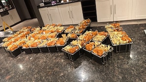A buffet setup with trays of food items arranged on a granite countertop. - Luxe Apartment - Stylish 2 Bedroom Apartment (Harrow)