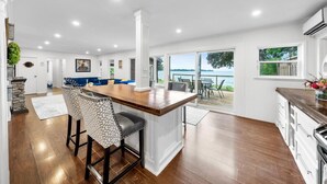 A spacious kitchen with a central island, large windows, and a view of the outdoors. - Redwood Retreat Waterfront Cottage By Simcoe With Hot Tub And Sauna (Orillia)