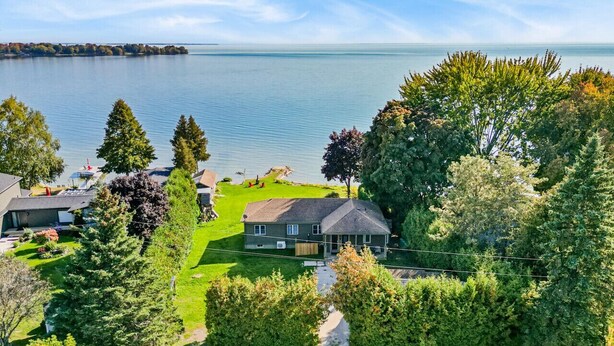 A house with a lawn and a view of a lake. - Redwood Retreat Waterfront Cottage By Simcoe With Hot Tub And Sauna (Orillia)