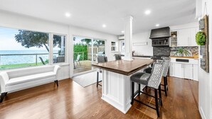 A modern kitchen with a large island, white cabinetry, and a view of the sea. - Redwood Retreat Waterfront Cottage By Simcoe With Hot Tub And Sauna (Orillia)