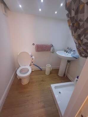 A small bathroom with a toilet, sink, and shower.