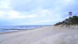 A beach with a lifeguard tower, sandy beach, and ocean. - Apartment in Dziwnówek near Baltic Beach (Dziwówek)