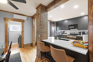 A modern kitchen with a central island, dark cabinetry, and a stone accent wall.