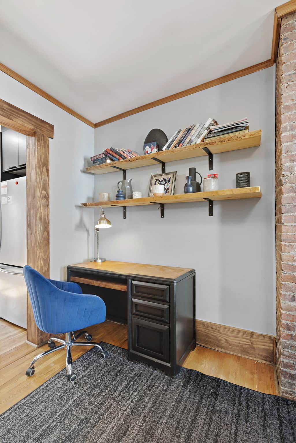 Un espace de bureau moderne comprenant un bureau, une chaise et deux étagères en bois sur lesquelles sont disposés divers objets.
