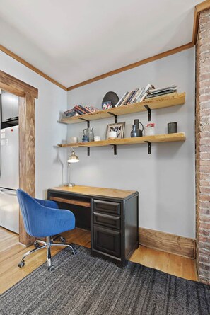 Un espace de bureau moderne comprenant un bureau, une chaise et deux étagères en bois sur lesquelles sont disposés divers objets.