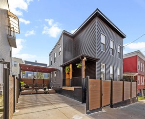 A two-story house with a covered patio area and a fenced backyard.