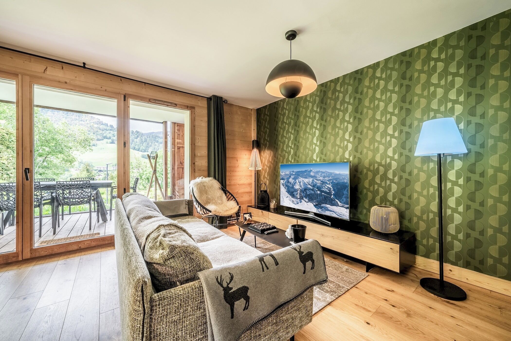 A modern living room with a sofa, TV, and a view of the outdoors.