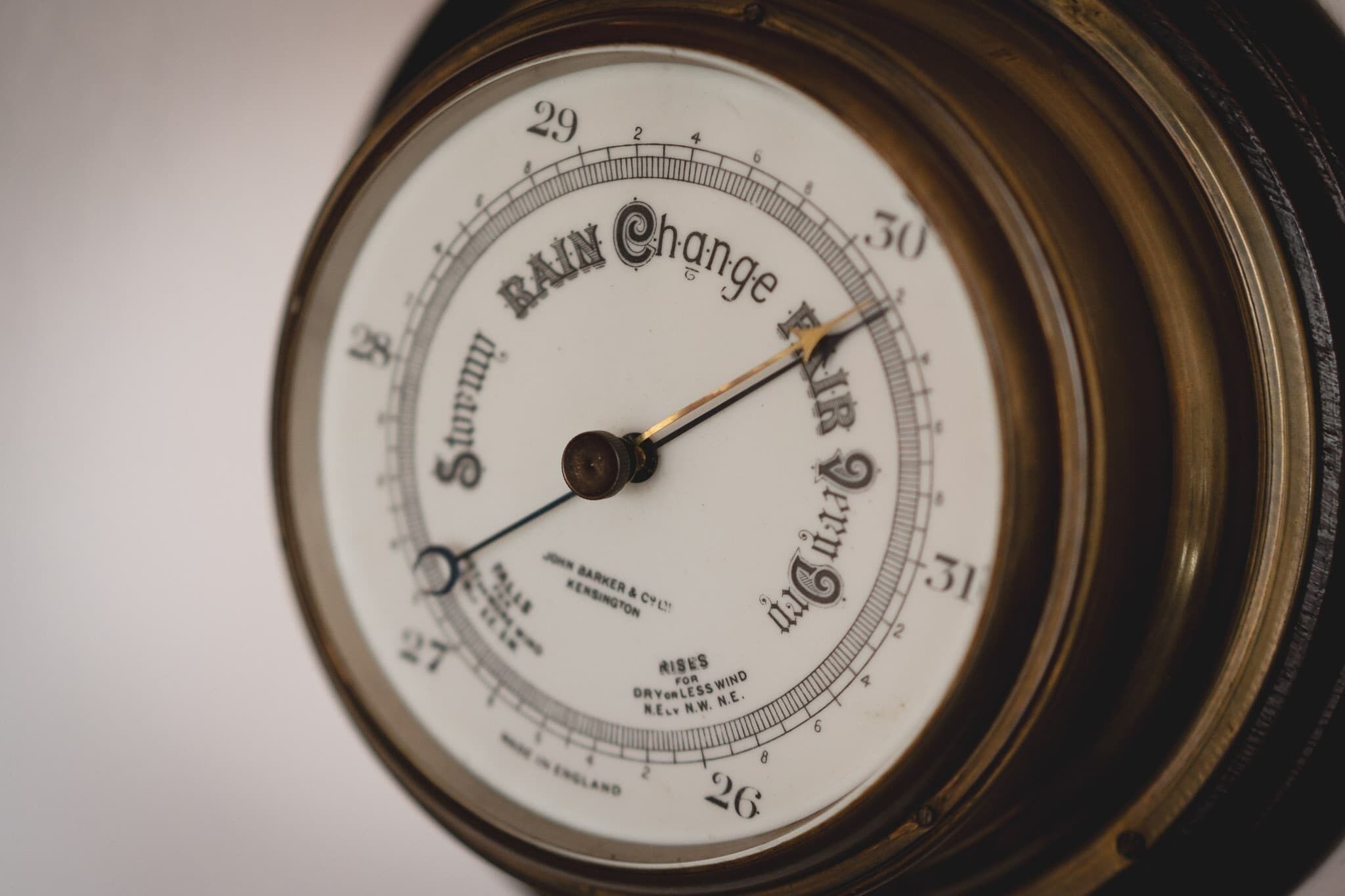 Gros plan d’un pluviomètre ancien portant la marque « Rain Change » et muni d’une échelle indiquant les mesures en pouces.
